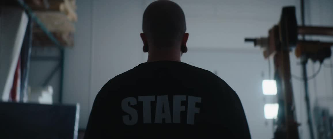 Man seen from behind wearing a shirt with the word staff in an industrial warehouse