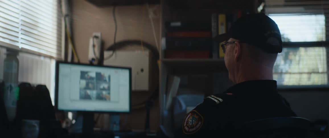 Uniformed man viewing images on a monitor inside a lit room