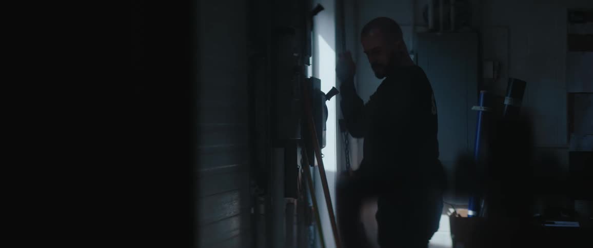Man opening a metal garage door lit by daylight
