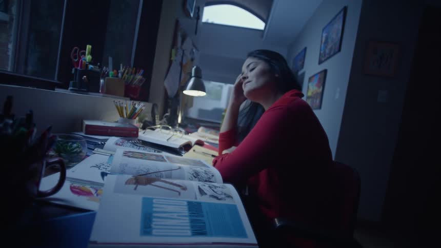 Woman sitting at a desk studying and resting her head with a tired expression