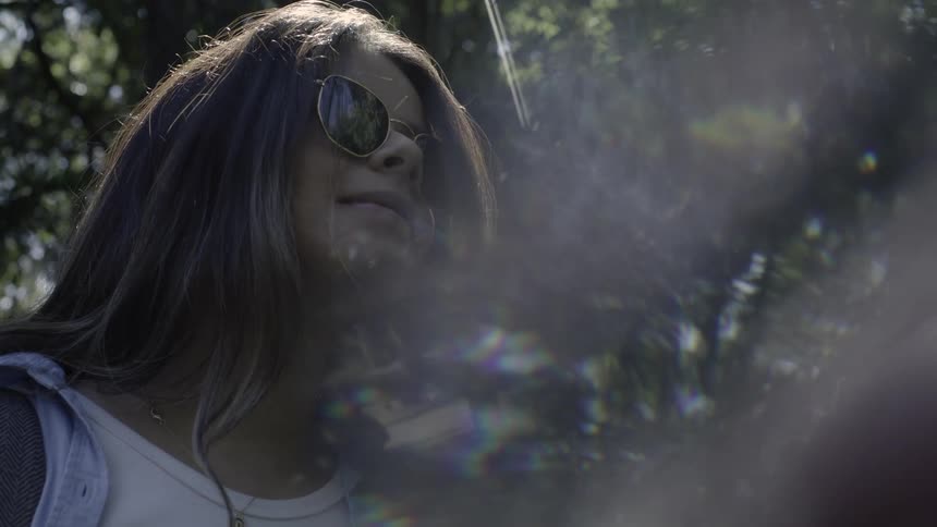 Person wearing sunglasses observing nature with light reflections around