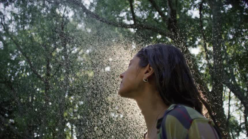 Close up portrait of a young woman standing outdoors under a drizzle during daytime