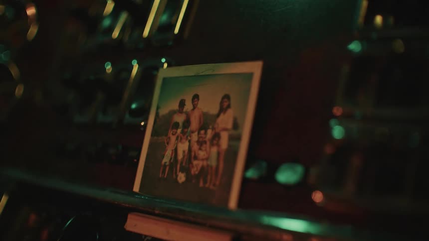 The video focuses on a framed or polaroidstyle photograph resting on the dashboard or interior console of a vehicle the photo which gradually comes into sharp focus shows a group of several peoplelikely a familystanding together outdoorsthe i