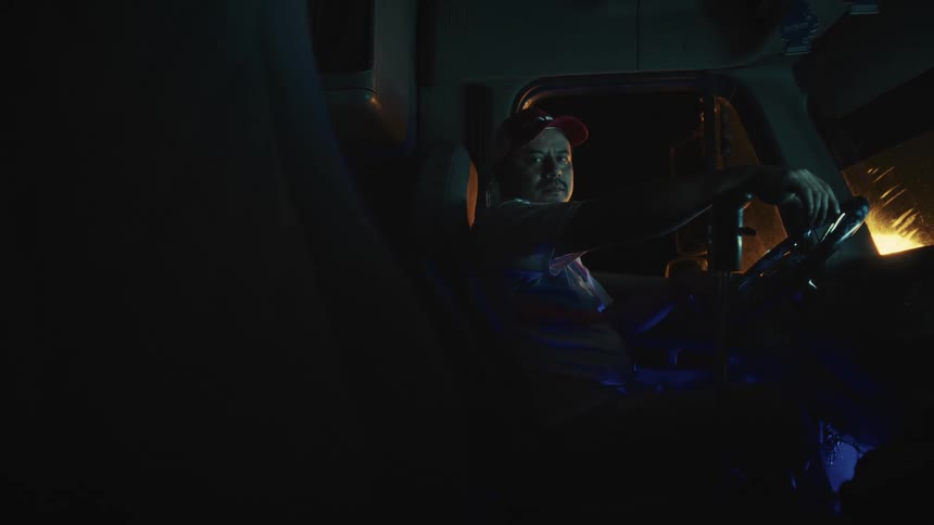 A middle aged hispanic male driver sitting in a cargo trailer at night