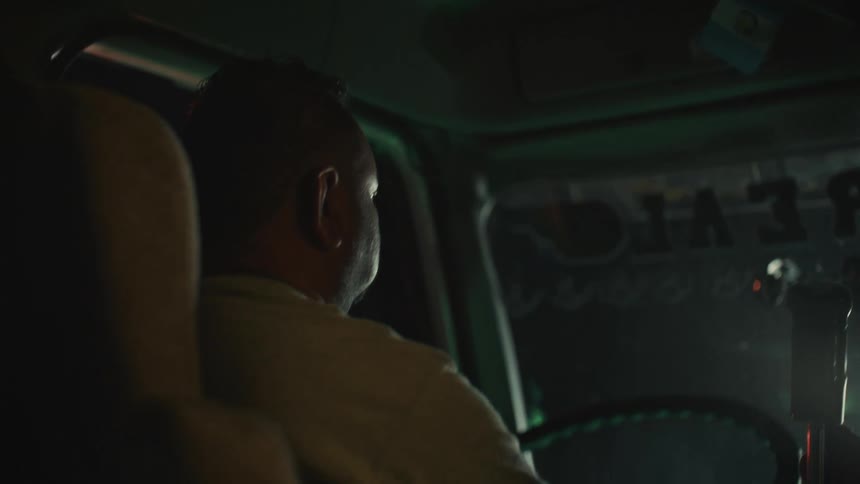 Driver seen in profile inside a truck cabin at night