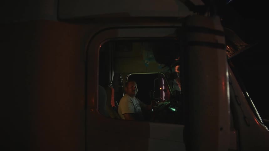 The man is sitting in the truck at night