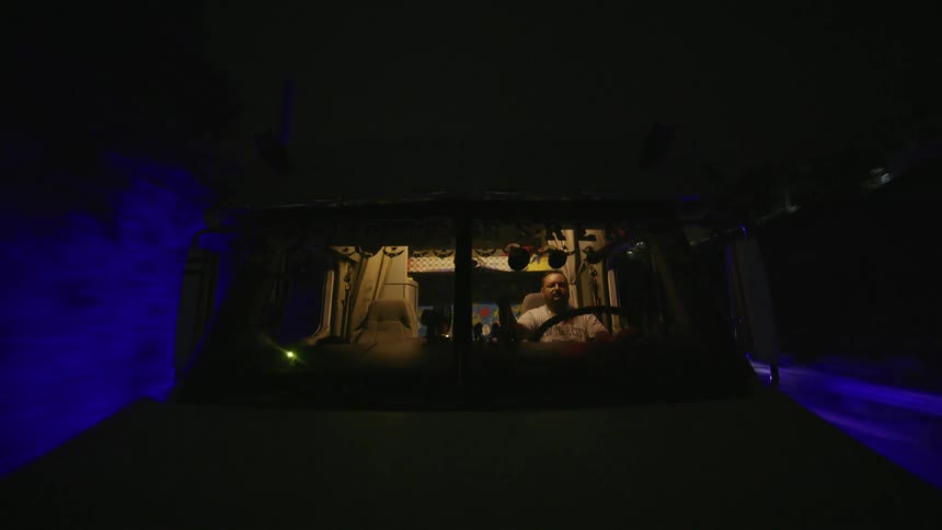 A man drives a large truck through a dark blue lit passage at night