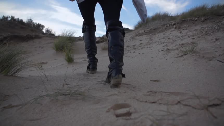 A woman climbing up a sand dune