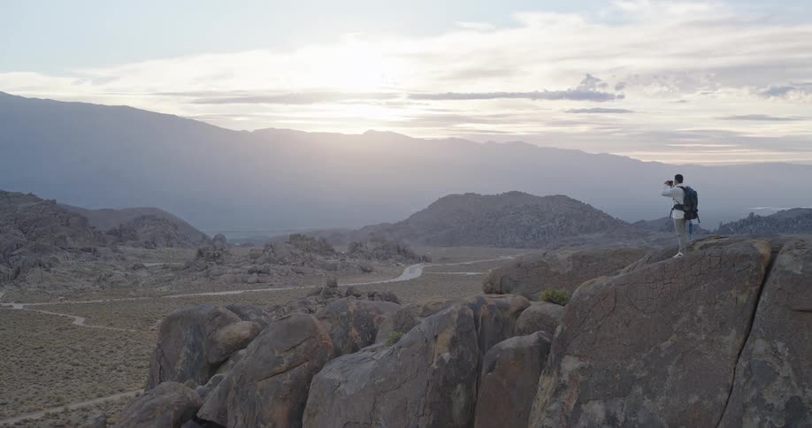 The hiker is using his binoculars on the tall rocks