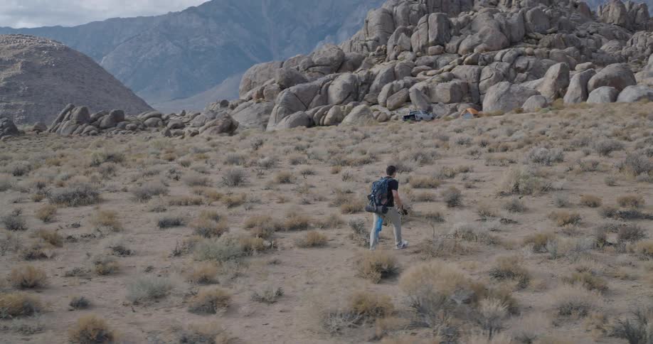 The man is hiking towards the mountains