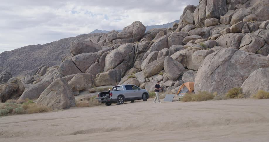 Man walking around a camp next to a rocky mountain outdoors during day time