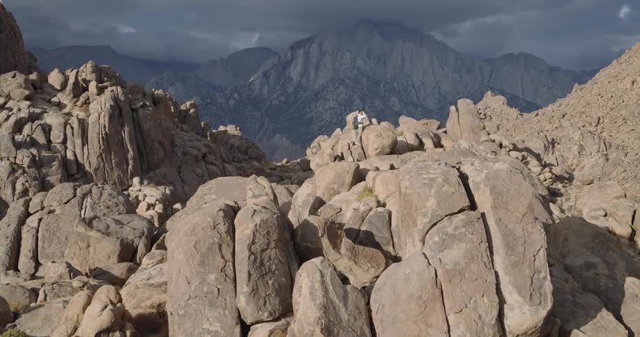 Man stands on a rock formation in a boulder field in mountainous terrain on a foggy autumn day