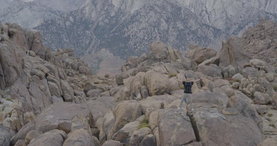 The black bird flies over the man on the boulders