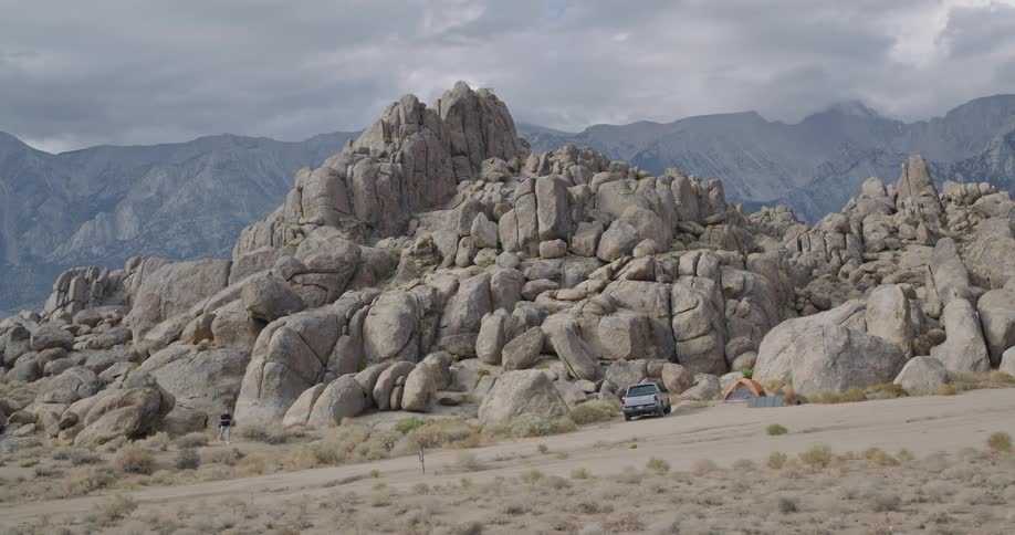 The man walks towards the truck by the boulders