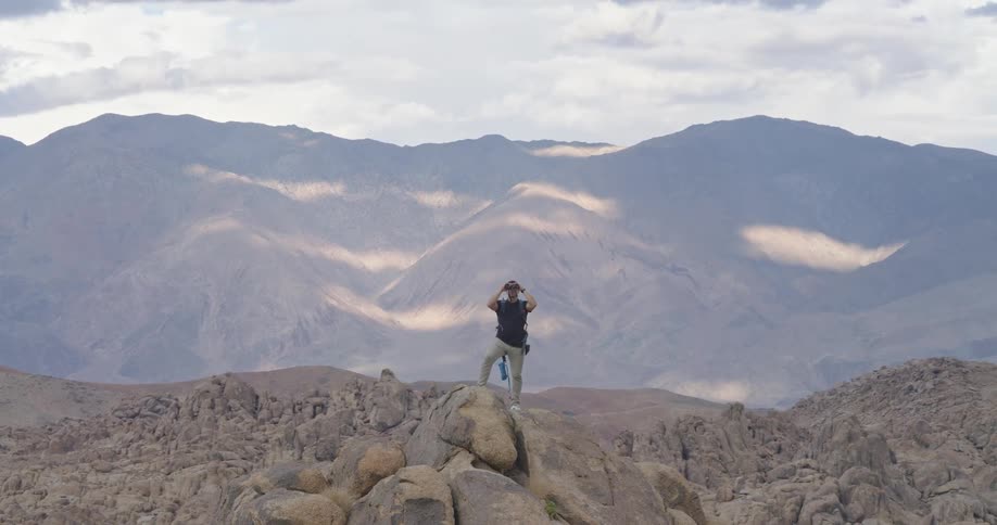Person observing landscape with binoculars on rock formation in mountainous area