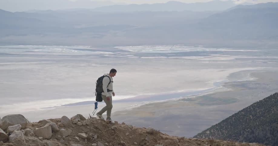 Male backpacker walks along a hill overlooking the beach on a foggy autumn day