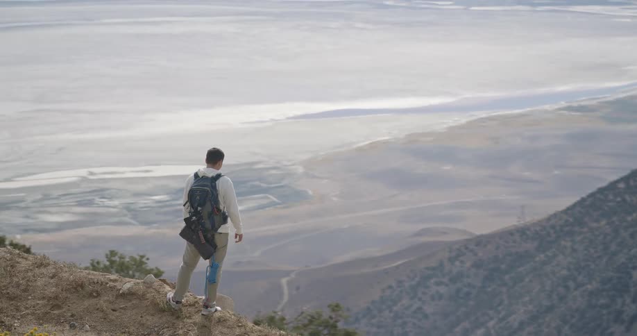 Man with backpack on rocky overlook observing forestcovered mountain landscape