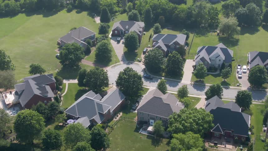 Singlefamily homes with lawns and curved streets in treelined suburban neighborhood