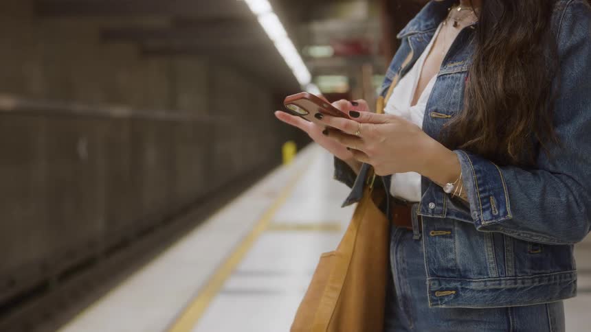 The woman is using her cell phone in the subway