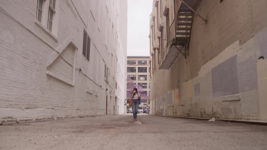 Woman walking and sipping from a cup in a suburban area outdoors during day time
