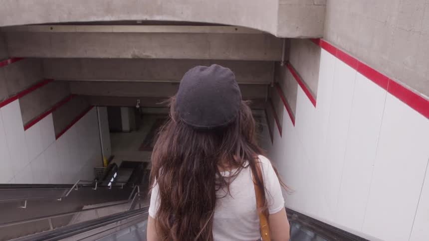 The woman is riding an escalator into the subway