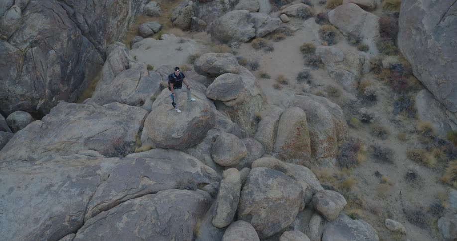 The man holds binoculars on the boulder