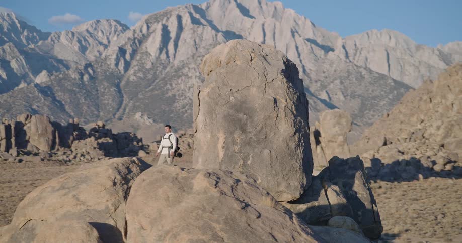 Person standing on rock formation with backpack in desert area