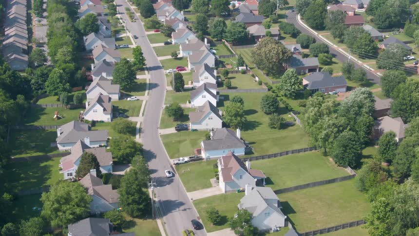 Residential street with aligned houses maintained lawns and scattered trees