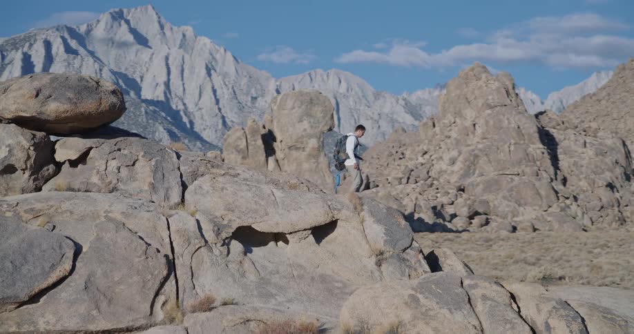 Man hiking among rock formations in mountainous and arid region