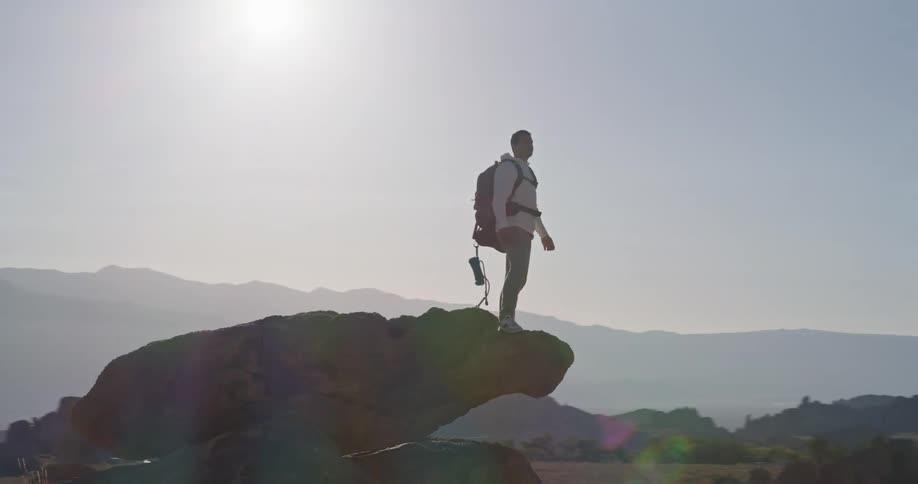 The man stands on the edge of a boulder and turns around