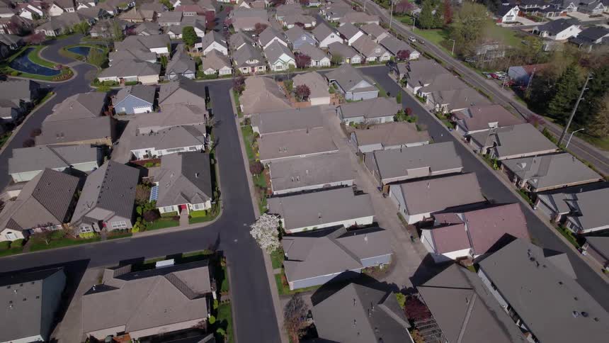 An aerial view captures a sprawling densely packed suburban neighborhood with similarstyle houses manicured yards and winding streets