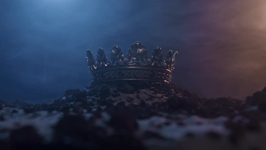 Metallic crown rests on rocky ground under blue and orange light with mist in the background