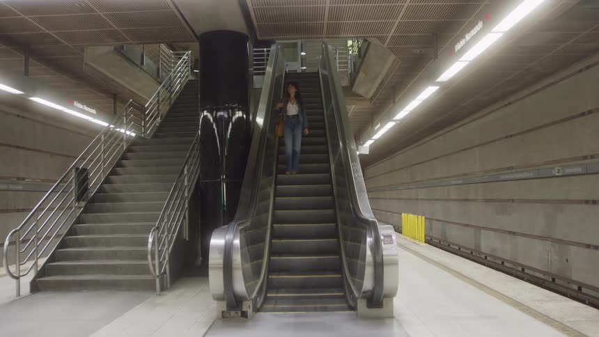Woman rides down an escalator located near a staircase