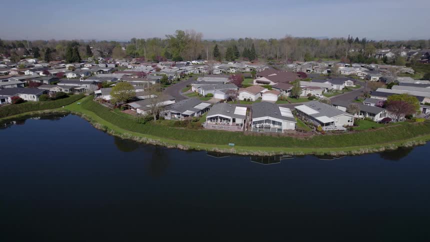 Suburban neighborhood with next to the shoreline with a lake to one side and a forest to another outdoors during day time