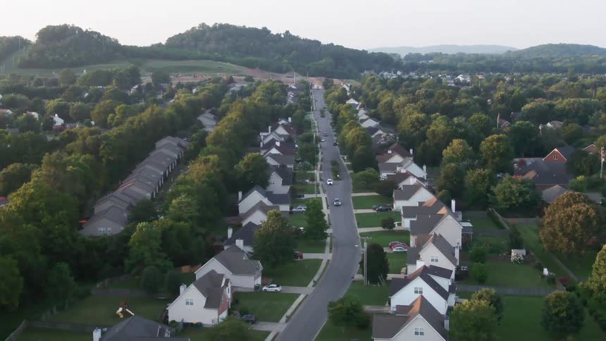 Aerial view of a residential neighborhood surrounded by trees and hills