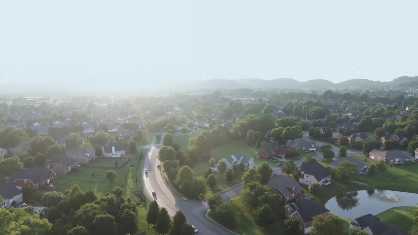 An aerial view of a suburban region with a highway running through it on a sunny day trees scattered across the area