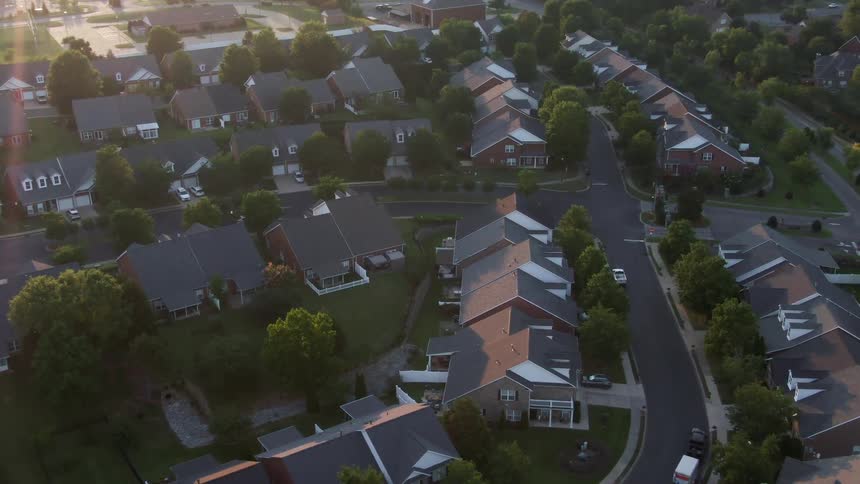 Suburban neighborhood seen from above with wellspaced houses curved streets and soft lateafternoon lighting