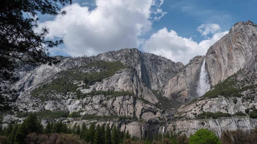 Yosemite falls cascading between granite cliffs surrounded by vegetation