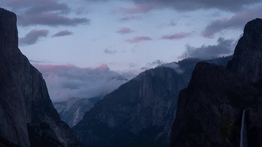 El capitan appears on the left and bridalveil fall on the right with low clouds between the cliffs
