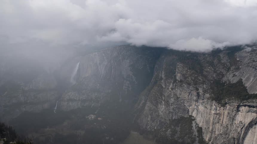 Waterfall plunging between granite cliffs under cloudy sky in yosemite