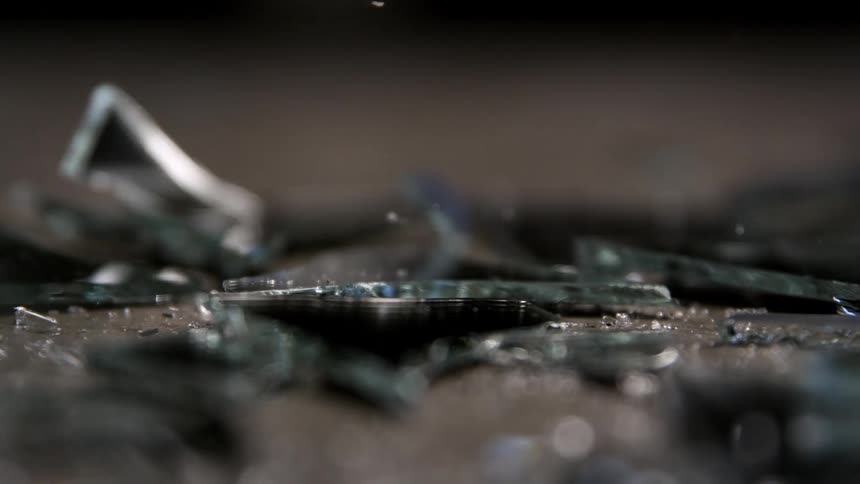 Shards of glass scattered on surface with particles suspended in the air