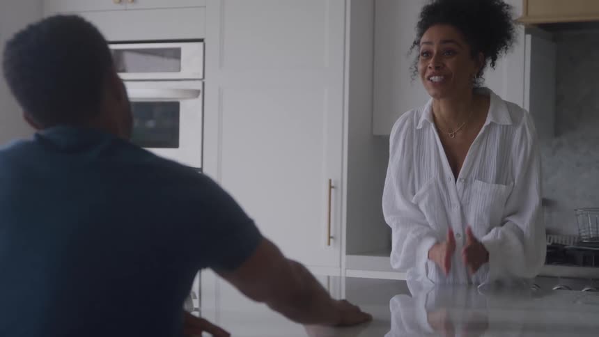 Man and woman share a serious conversation over a kitchen countertop