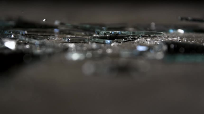 A glass shards scatter across a surface in slow motion