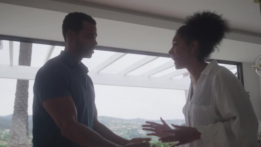 A couple is engaged in a tense conversation in a living room