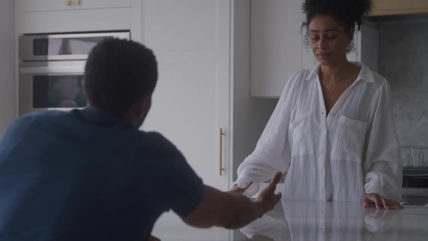 A couple are engaged in a tense argument in a modern kitchen