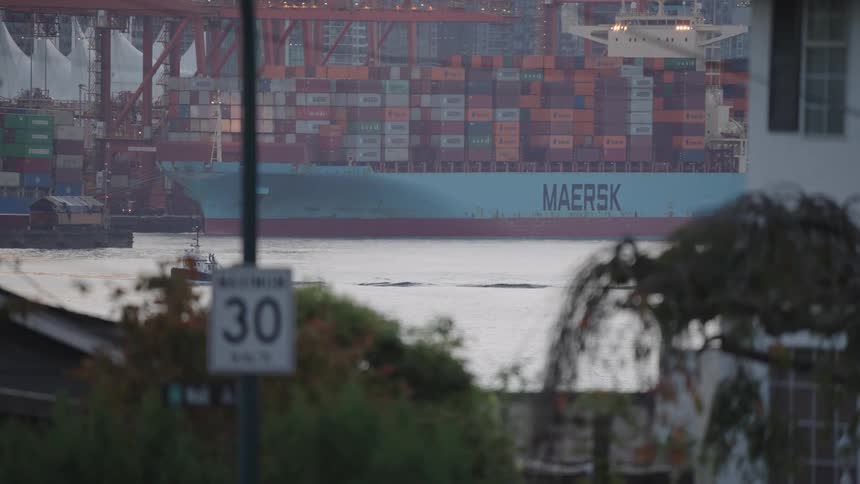 The tugboat travels past the container yard