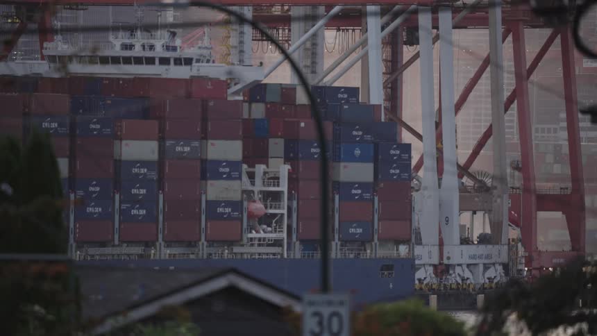 Docked cargo ship carrying containers near residential area