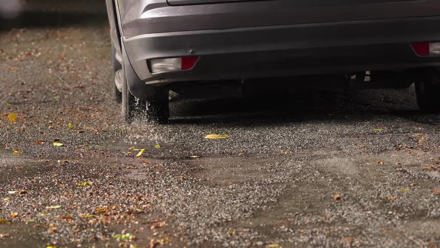 Gray car in motion on wet road with scattered stones and leaves highlighting dynamic interaction with terrain