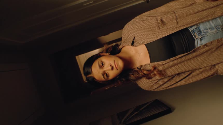 Woman stands in the hallway with a worried expression and steady gaze