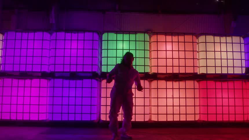 A woman dances in front of a wall of colorful illuminated cubes